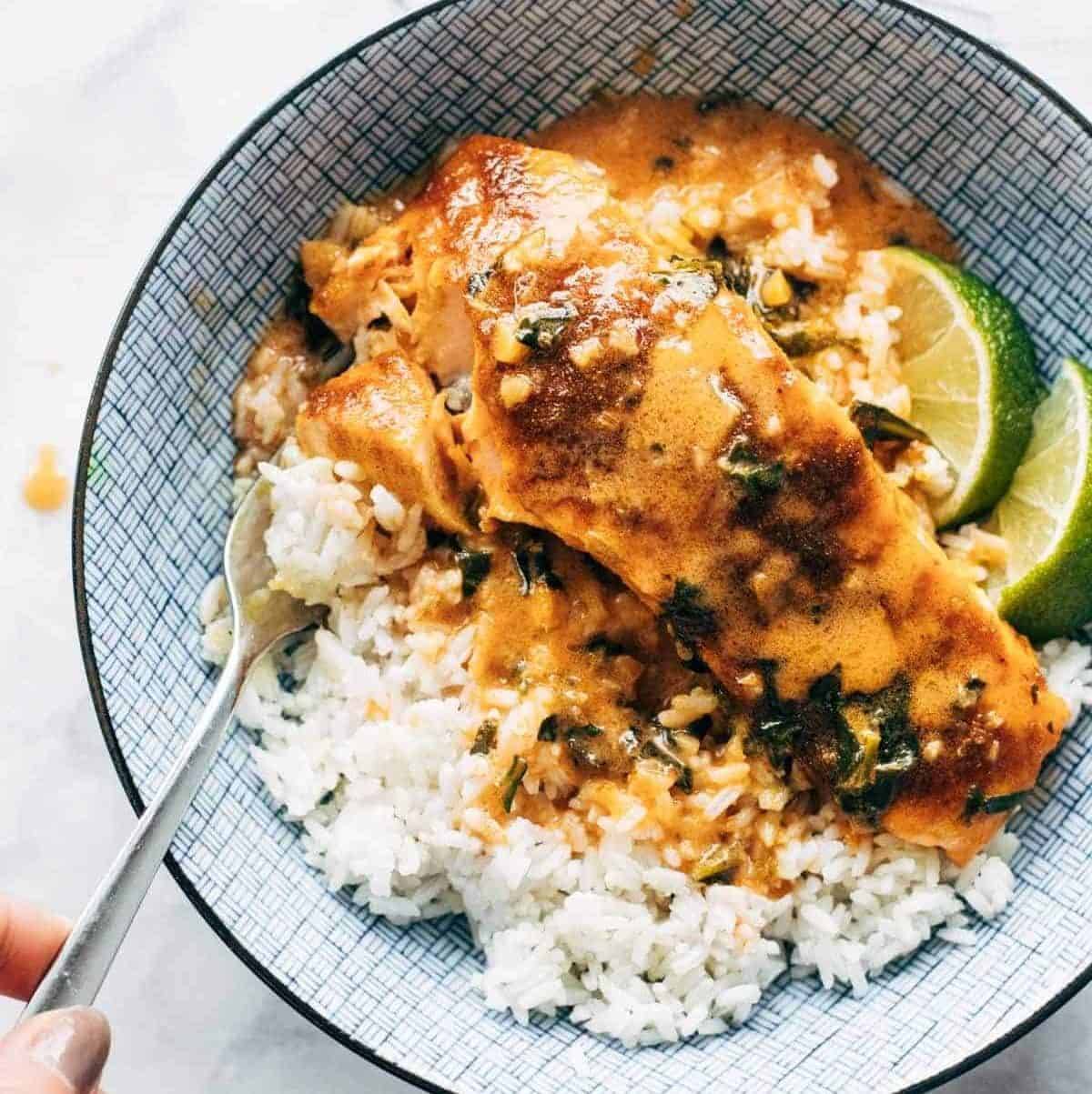Salmon curry in a bowl with rice and limes.