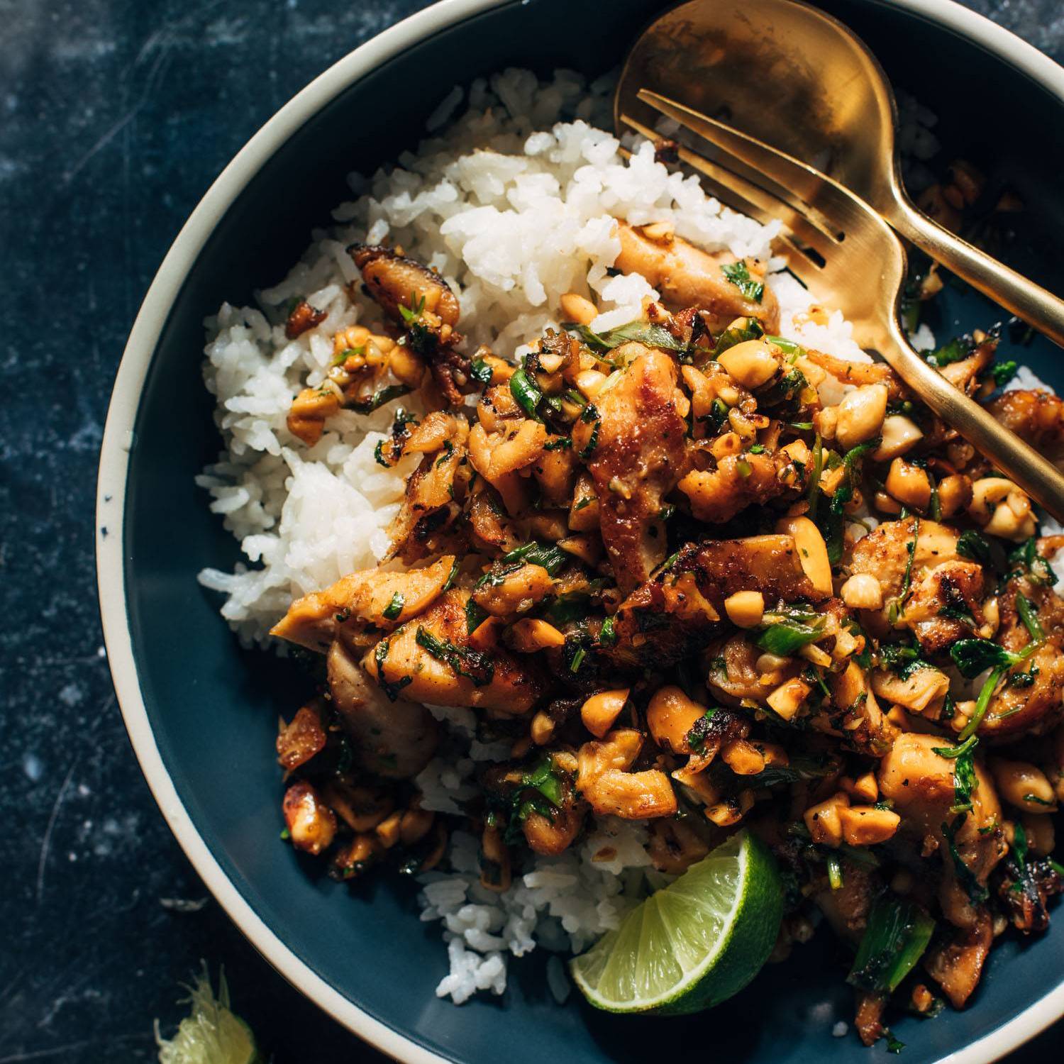 Ginger peanut chicken in a bowl with rice and a lime wedge.